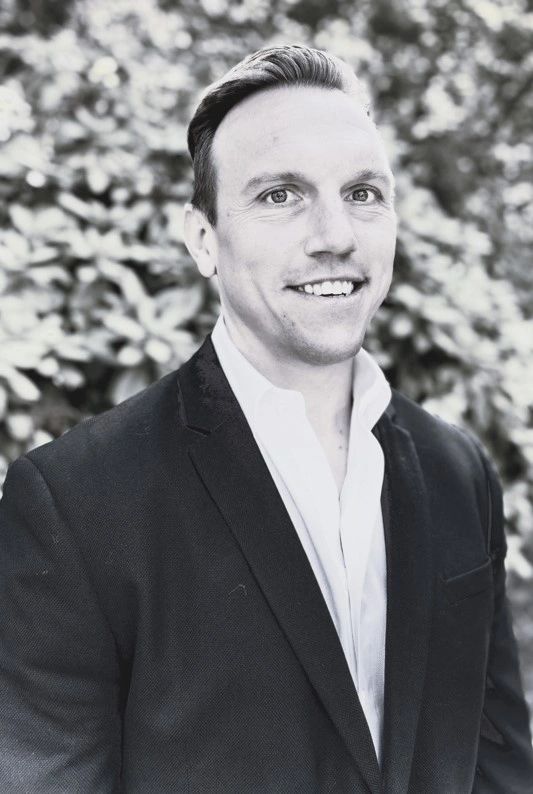 A man in a suit and tie smiling for the camera.